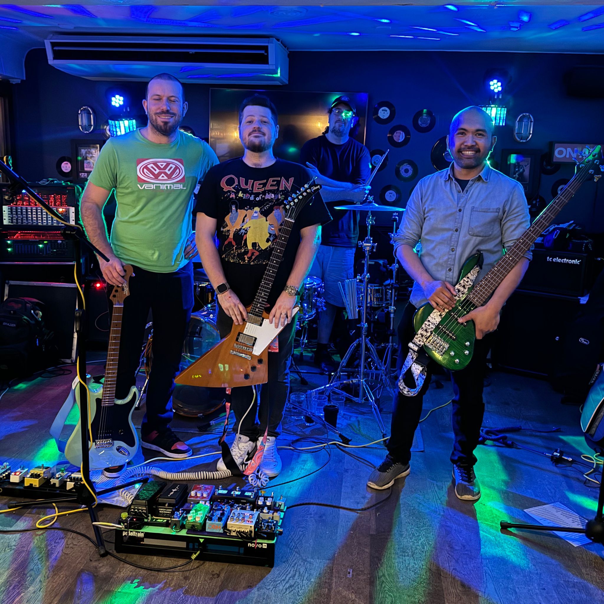 Four musicians with guitars on a stage with colorful lighting